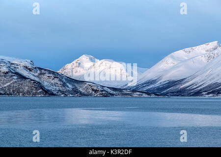 Blue sky and snowy peaks surround the cold sea Lyngen Alps Tromsø Lapland Norway Europe Stock Photo