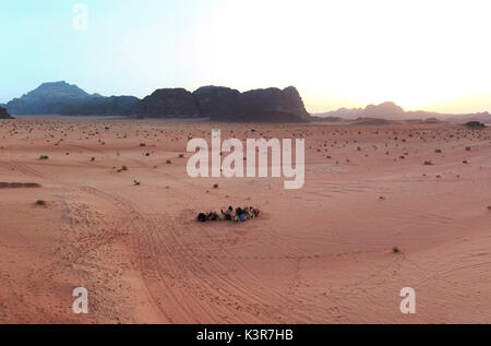 Sunset in the Wadi Rum desert, Jordan, with local bedouins and camels on foreground Stock Photo