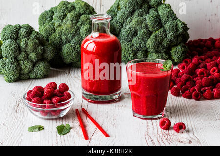 healthy drinks. raspberry fresh smoothie in glass and bottle with berries on white wooden background. Stock Photo