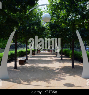 The oak tree lined path at Klyde Warren Park in Dallas features seating and decorative archways. Stock Photo