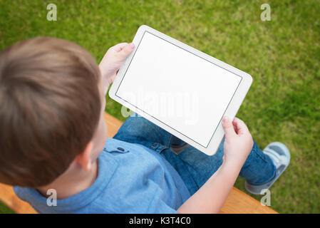 Boy use tablet with isolated white screen for mockup. Child playing game, surfing or watching cartoon. Stock Photo