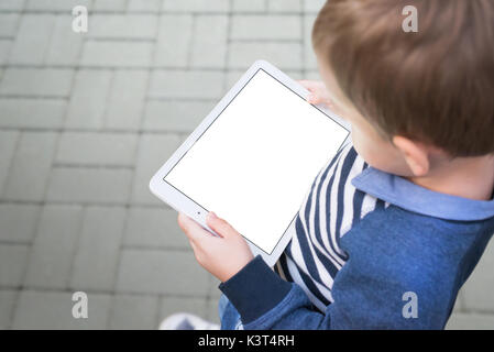 Boy holding tablet on city street. Device with isolated screen for mockup, template, product presentation. Stock Photo