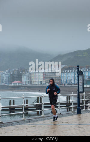 Aberystwyth Wales UK, Monday 04 September 2017 UK Weather: A man jogging along the deserted promenade out on a dull, misty and humid morning, with drizzle and rain in Aberystwyth Wales photo Credit: Keith Morris/Alamy Live News Stock Photo