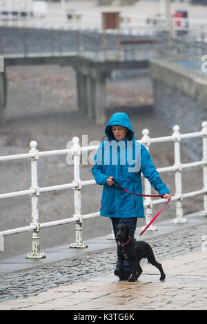 Aberystwyth Wales UK, Monday 04 September 2017 UK Weather: A woman in her bluw rain jacket walking her dog along the deserted promenade on a dull, misty and humid morning, with drizzle and rain in Aberystwyth Wales photo Credit: Keith Morris/Alamy Live News Stock Photo