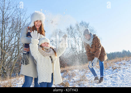 Family playing snowballl fight and having fun in winter Stock Photo