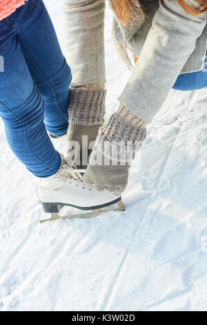 Mother binds shoes for daughter before going ice-skating Stock Photo