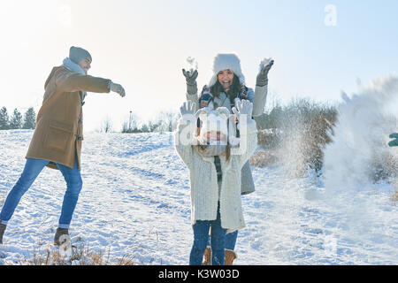 Family in snowball fight having fun with joy in winter Stock Photo
