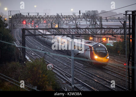 From London Virgin Alstom Class 390 Pendolino at Ardwick leading to Manchester Piccadilly station on the  West Coast Main Line WCML in the fog and rai Stock Photo