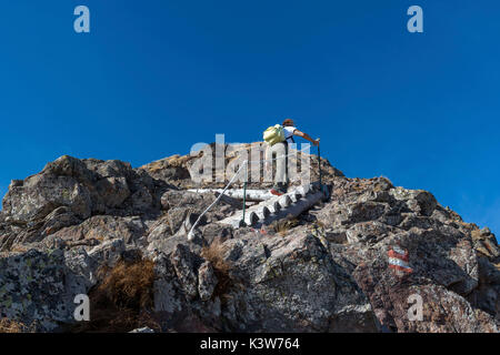 Italy, Trentino Alto Adige, Non valley, woman hiker climbs to the summit of Luco Mount on the steep wooden stairs. Stock Photo