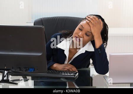Young Depressed Businesswoman Sitting At Office Desk Stock Photo