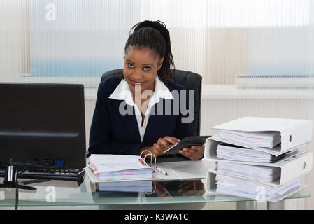 Young African Businesswoman Calculating Bills Using Calculator Stock Photo