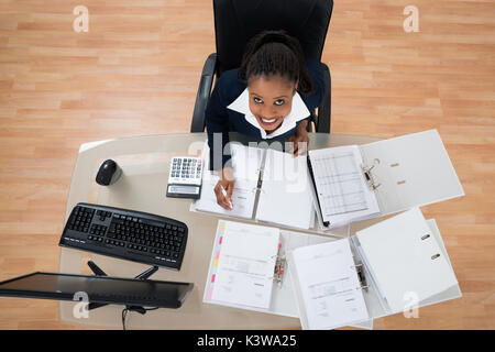 High Angle View Of Businesswoman Calculating Bills Using Bills Stock Photo
