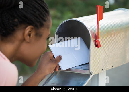Close-up Of Woman Putting Letter In Mailbox Stock Photo