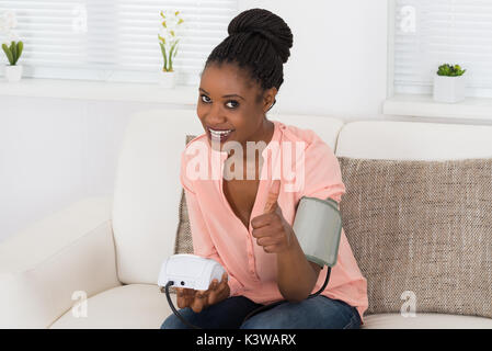 Smiling Young Woman Measuring Her Blood Pressure Stock Photo