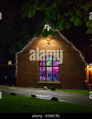 A party inside a building,viewed from outside at night, coloured lights,disco lights, Stock Photo