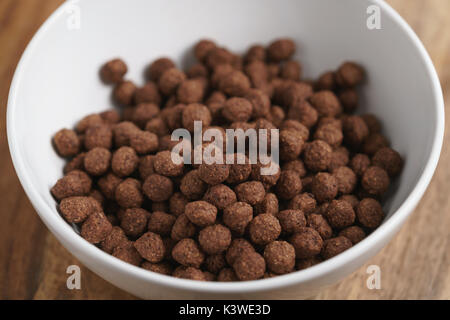 chocolate cereal balls in white bowl for breakfast on wooden table Stock Photo