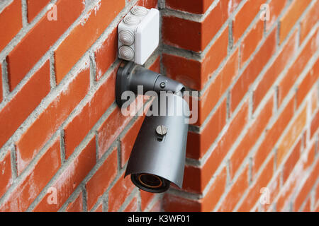 A video camera on a red brick wall protects the territory from the invasion of strangers Stock Photo