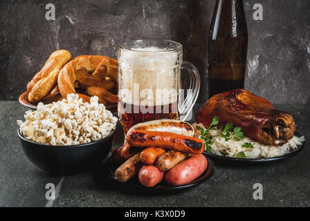 Selection of traditional German food Oktoberfest. Beer, baked pork shank, popcorn, assortment of different sausages, homemade bretzels. On a black sto Stock Photo