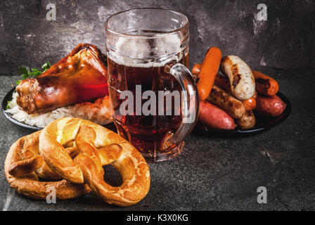 Selection of traditional German food Oktoberfest. Beer, baked pork shank, popcorn, assortment of different sausages, homemade bretzels. On a black sto Stock Photo