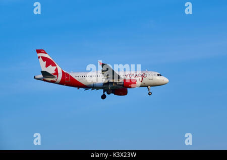MONTREAL, CANADA - AUGUST 28, 2017 : Landing C-GKOB Air Canada Rouge Airbus A319. Stylized Air Canada rouge, is the vacation and leisure airline subsi Stock Photo
