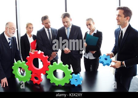 Business people assembling cogwheels, teamwork concept Stock Photo