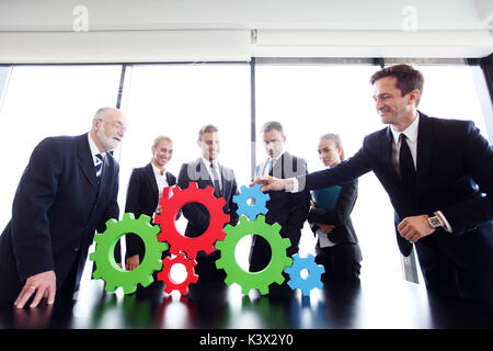 Business people assembling cogwheels, teamwork concept Stock Photo