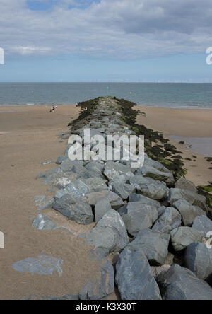 Rock boulder groyne with sand build up on porth eirias beach, part of Coastal sea defences at colwyn bay in north wales uk Stock Photo