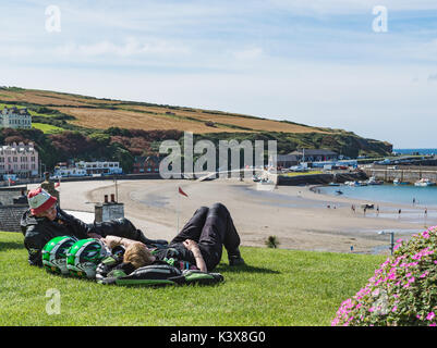 Bikers lying on the grass looking across Port Erin beach Stock Photo