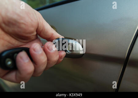 man's hand opens the car door with a key. Stock Photo