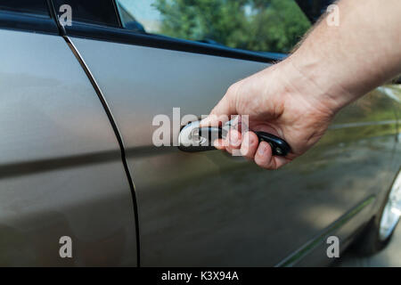 man's hand opens the car door with a key. Stock Photo