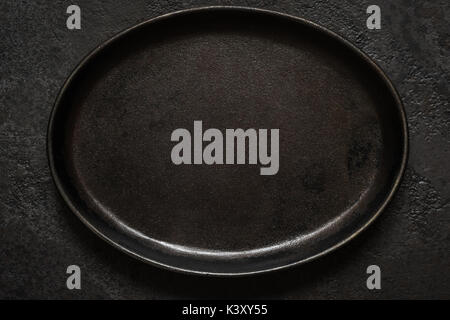 Empty rustic black cast iron plate On Dark concrete background. Top view with copy space. Stock Photo