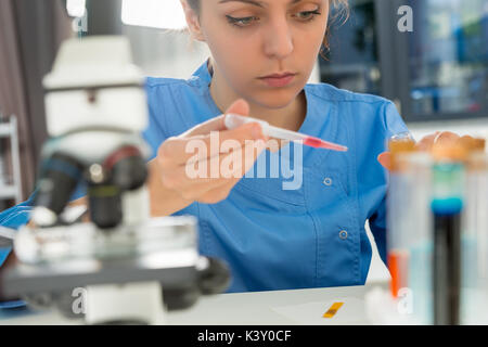 Young concentrated female scientist in uniform working on some research in a laboratory. Healthcare and biotechnology concept Stock Photo