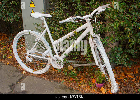 The modern phenomenon of a memorial Ghost Bike chained to a post at the scene of a tragic fatal accident involving a motor vehicle and a cyclist on th Stock Photo