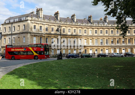 A red tourist bus arriving at The Circus, Bath, Somerset, England, UK. A UNESCO World Heritage Site. Stock Photo