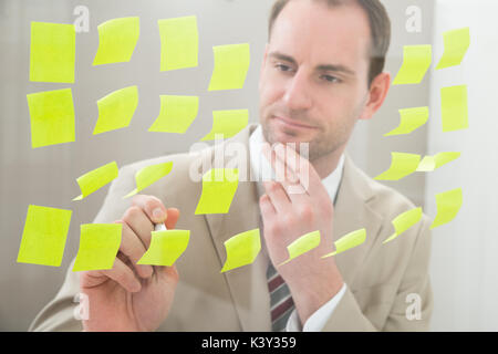 Contemplating Businessman Making Notes On Adhesive Paper Stock Photo