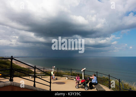 Mother and children on the cliff top at Saltburn North Yorkshire with a heavy rain storm approaching over the sea Stock Photo