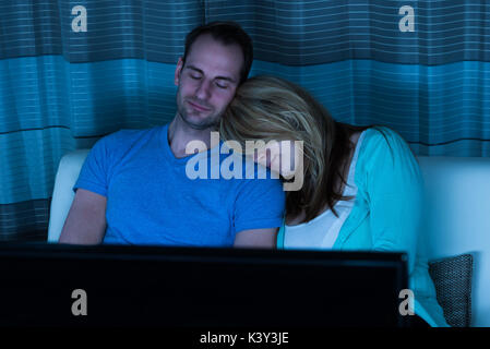 Couple Sleeping On Sofa In Front Of Television At Home Stock Photo