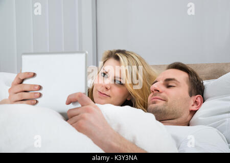 Happy Couple Using Digital Tablet In Bed At Home Stock Photo