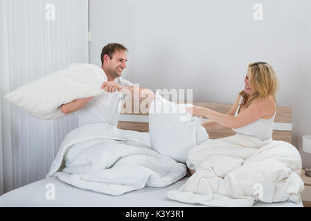 Happy Couple Fighting Together With Pillows On Bed Stock Photo