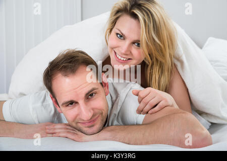 Portrait Of Happy Woman Lying On Back Of Man Stock Photo