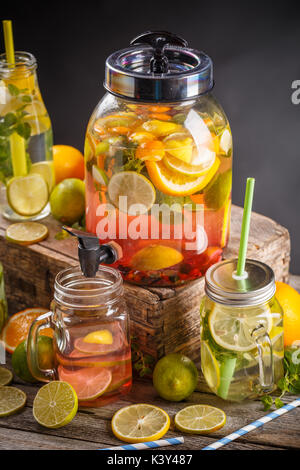 Refreshing summer drink with red berries and limes in a jug and glasses on the vintage wooden table Stock Photo
