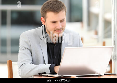 Single executive working writing on line in a laptop sitting in a coffee shop Stock Photo
