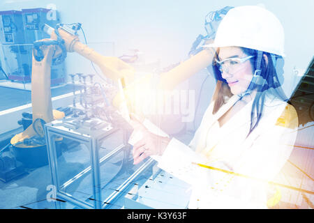 Double exposure of Manufacturing production industrial machine , factory robots arm in smart factory , engineer female using tablet for check monitori Stock Photo