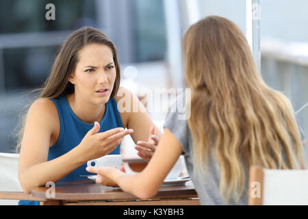 Two angry girls talking seriously sitting in a coffee shop Stock Photo