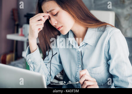 Stressed Asian creative designer woman cover her face with hand and feel upset from work in front of laptop computer on desk at office,Stress office l Stock Photo