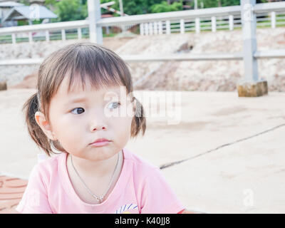portrait of little girl scowling face playing in the park and soft focus ,asian baby Stock Photo