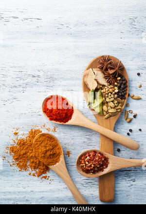 Wooden spoon filled with spices on white painted table Stock Photo
