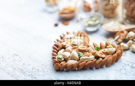 Mixed nuts forming a heart-shape on white painted wood background Stock Photo