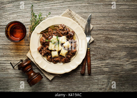 Fresh fried chicken liver with onion and gnocchi on wooden table Stock Photo