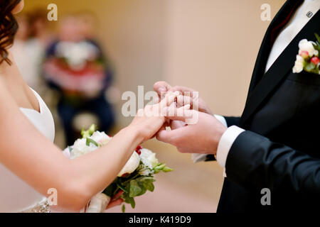 Beauty bride and handsome groom are wearing rings each other Stock Photo